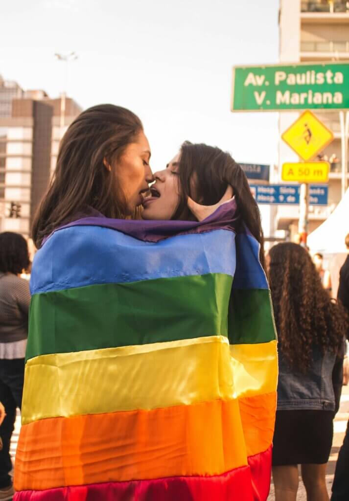 lesbian women kissing each other wearing the lgbtq flag