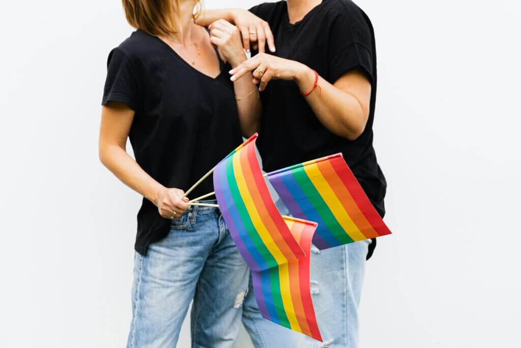 λεσβίες με μαύρα tshirts που κρατούν lgbtq+ σημαίες
