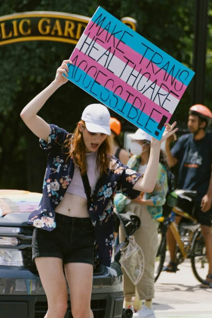 trans με πλακάτ που διεκδική την ίση πρόσβαση στη δημόσια υγεία και περίθαλψη όλων των ατόμων