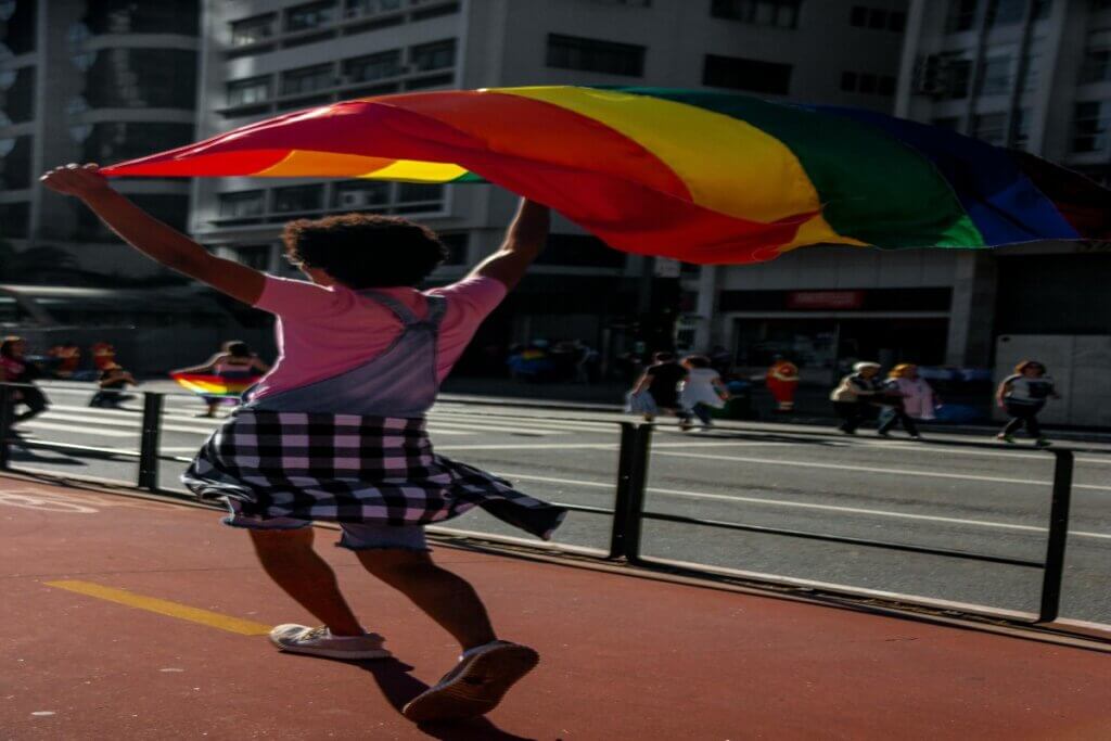 LGBTQ+ γυναίκα γυρισμένη πισώπλατα ενώ περπατάει με πολύχρωμη σημαία να ανεμίζει